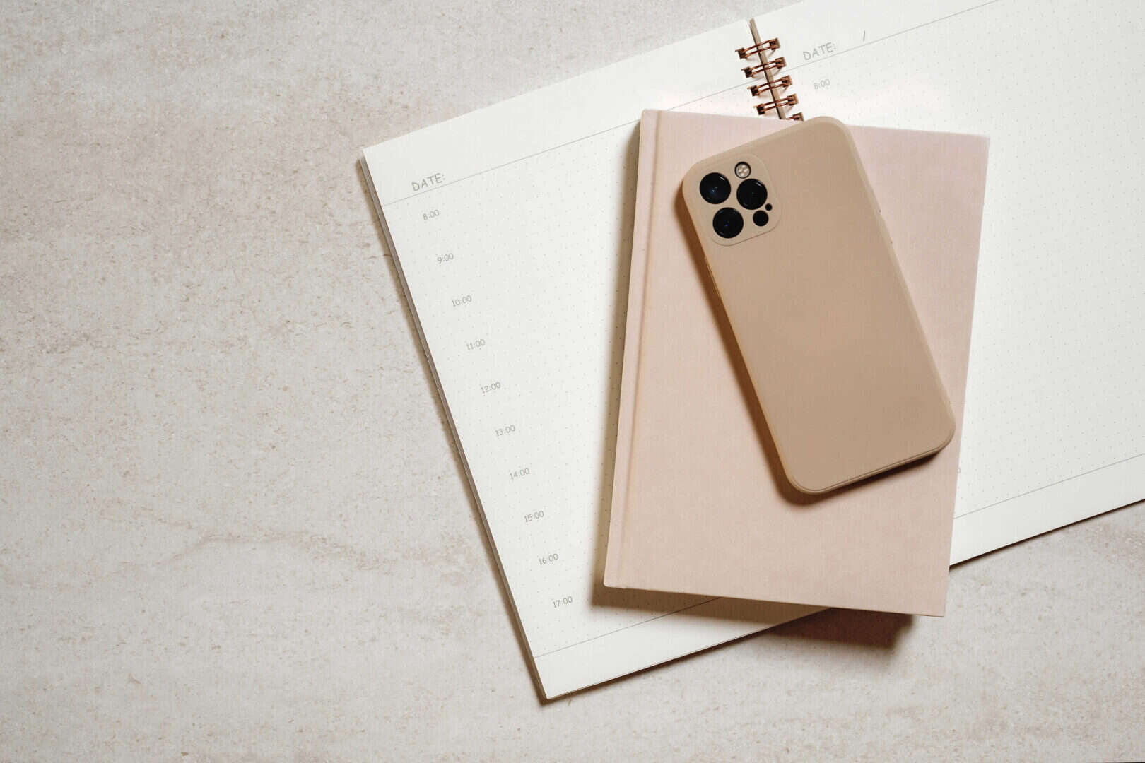 Flatlay of smartphone on planner and open daily schedule page for digital and paper planning.
