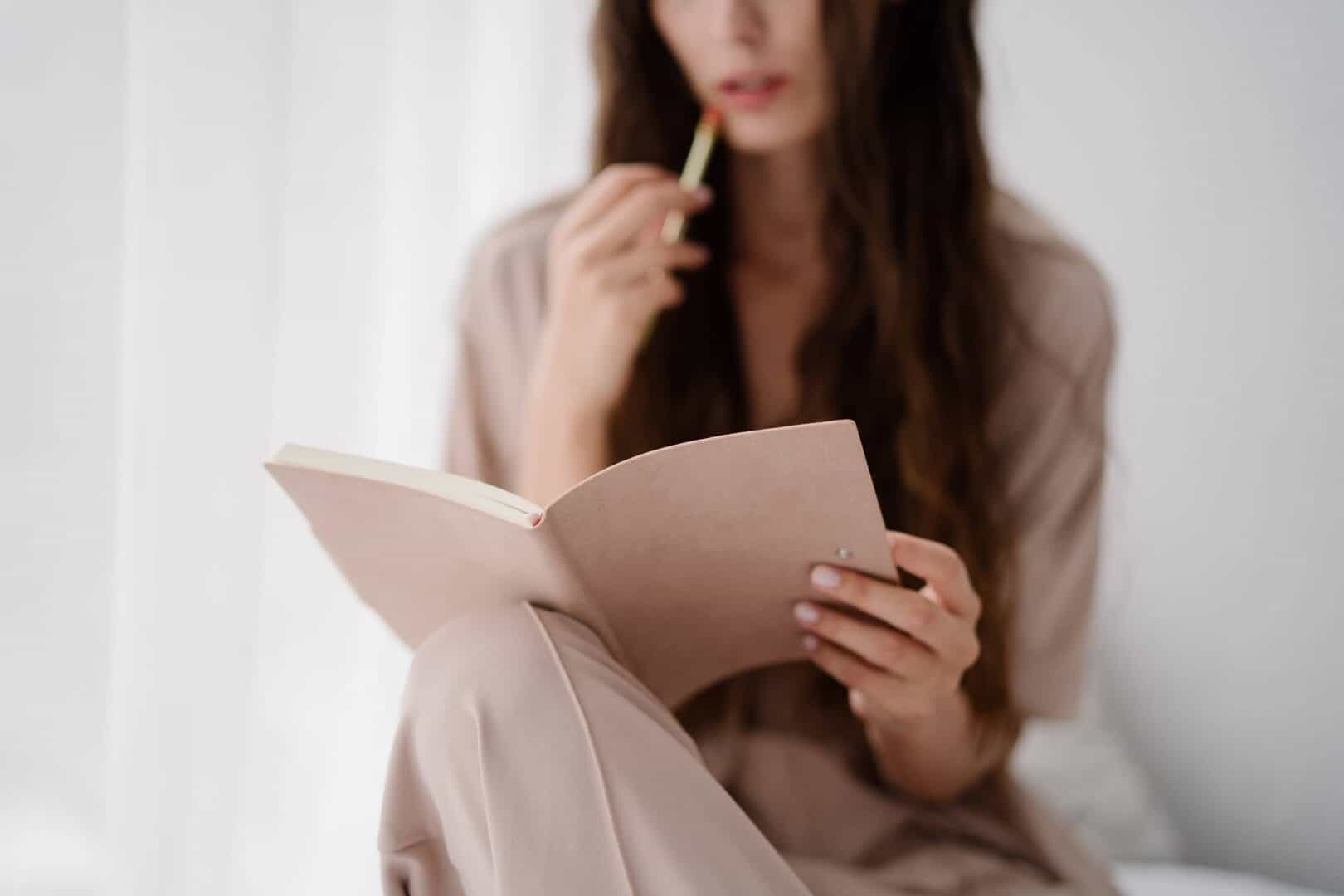 Mom reflecting with a printable planner journal, building habits and planning routines.