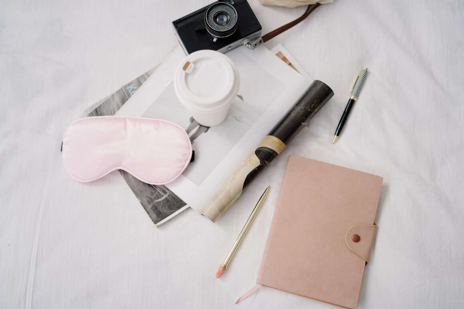 Flatlay with planner, pink sleep mask, coffee, and camera styled for self-care planning.
