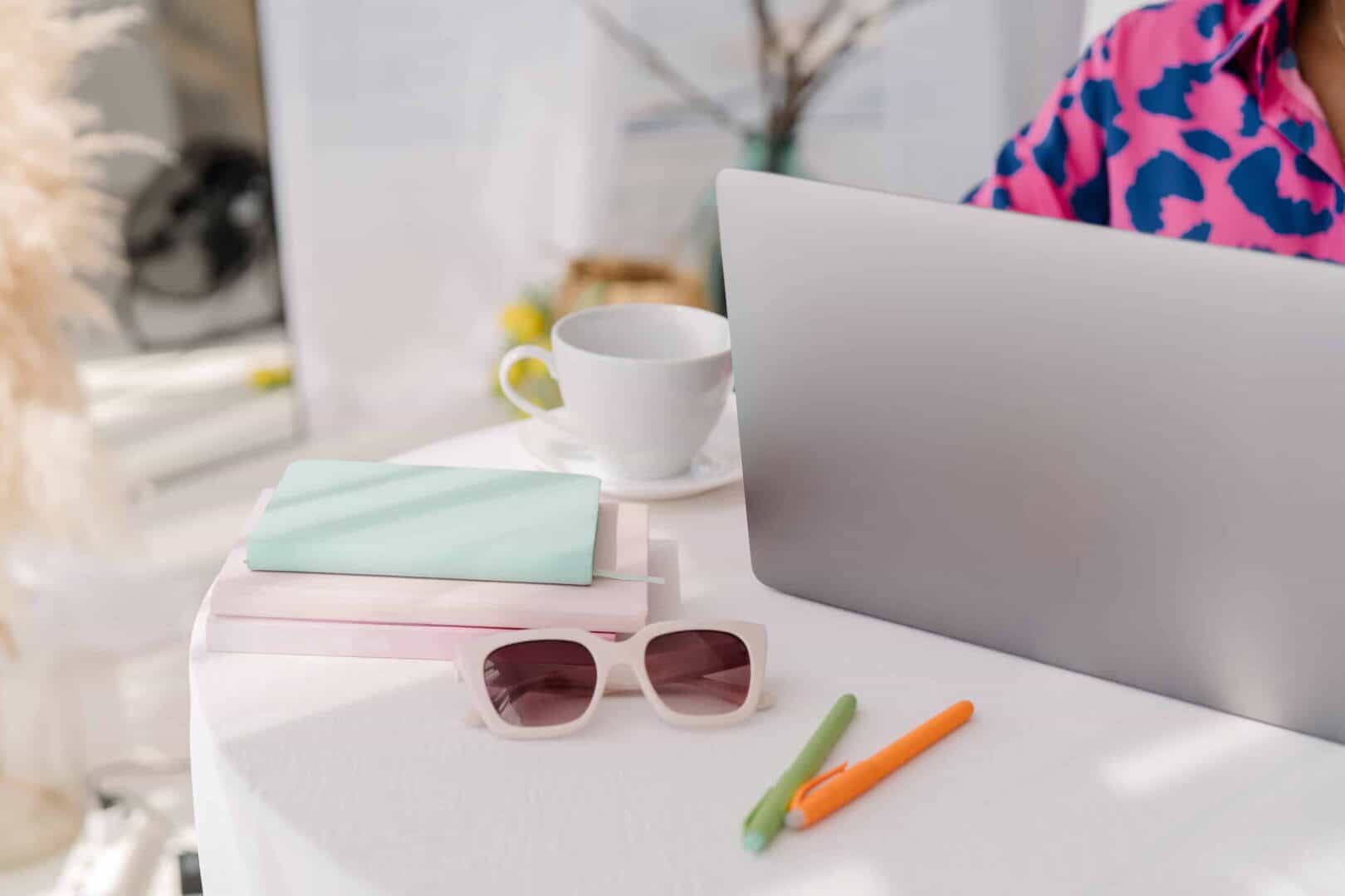 Laptop with coffee, notebooks, and pens on a desk for digital planning routine.