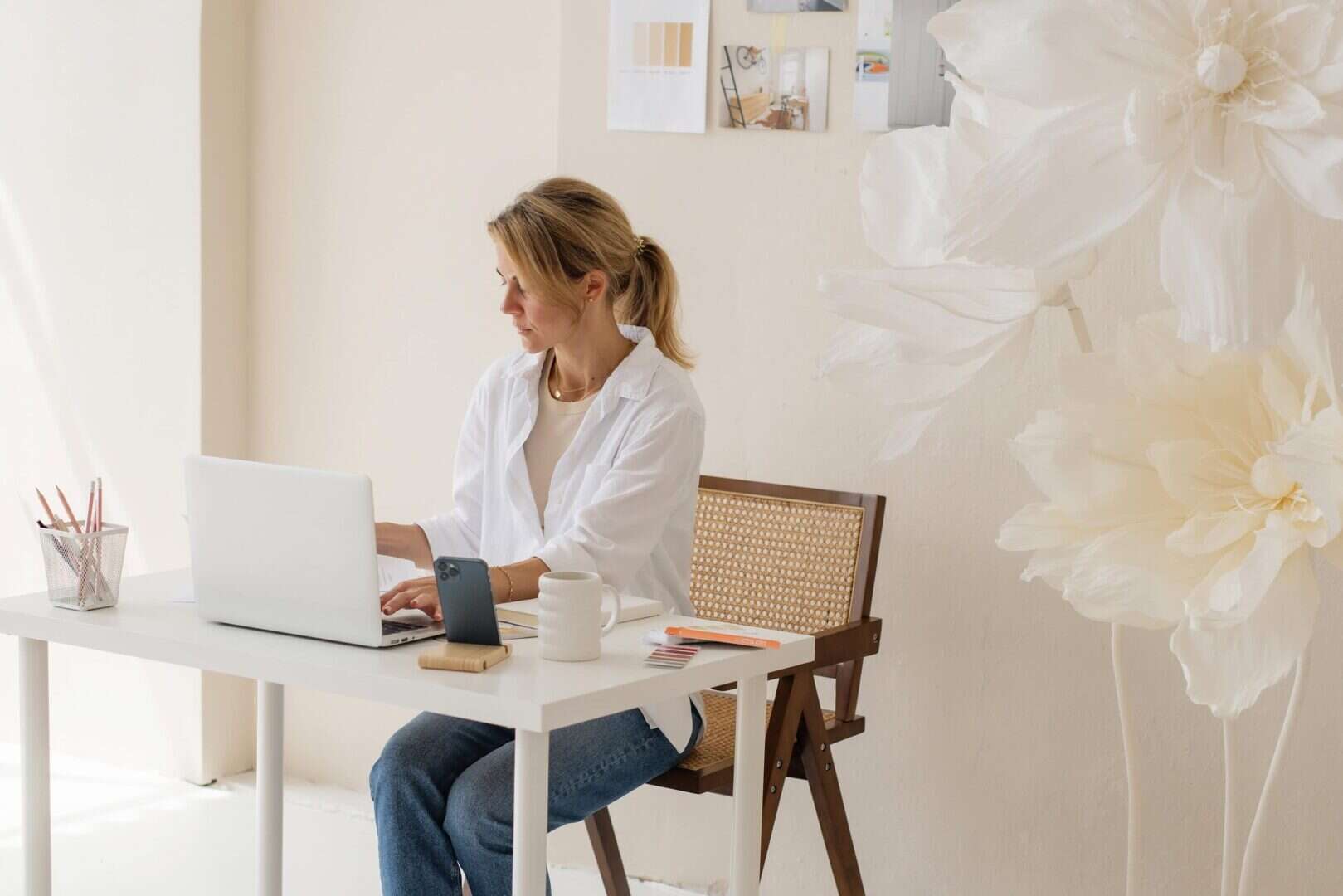 Woman working on laptop at a bright desk, representing digital planning tools for entrepreneurs and mompreneurs.