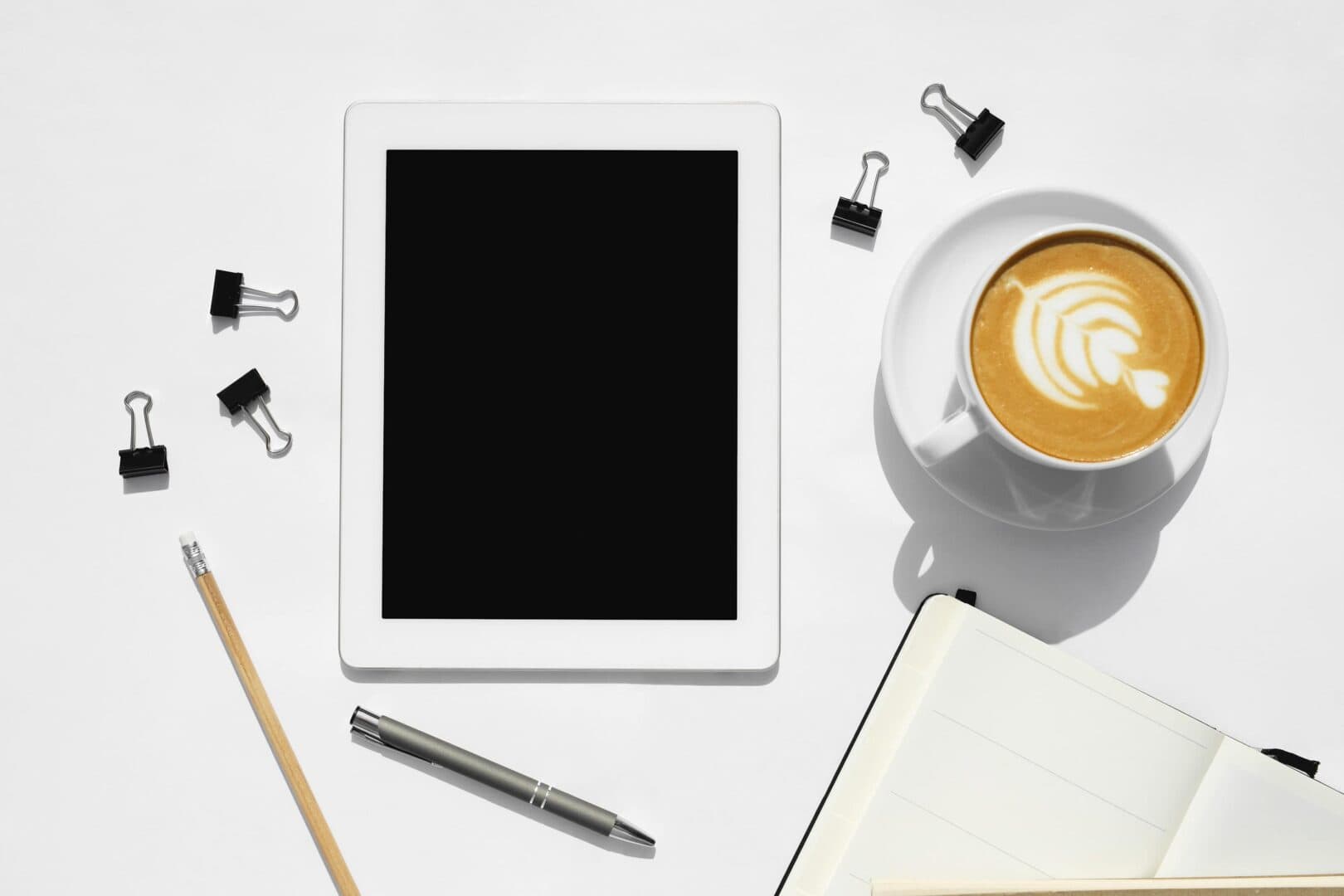Tablet and open notebook with coffee on desk, showing digital vs printable planners setup for daily planning.